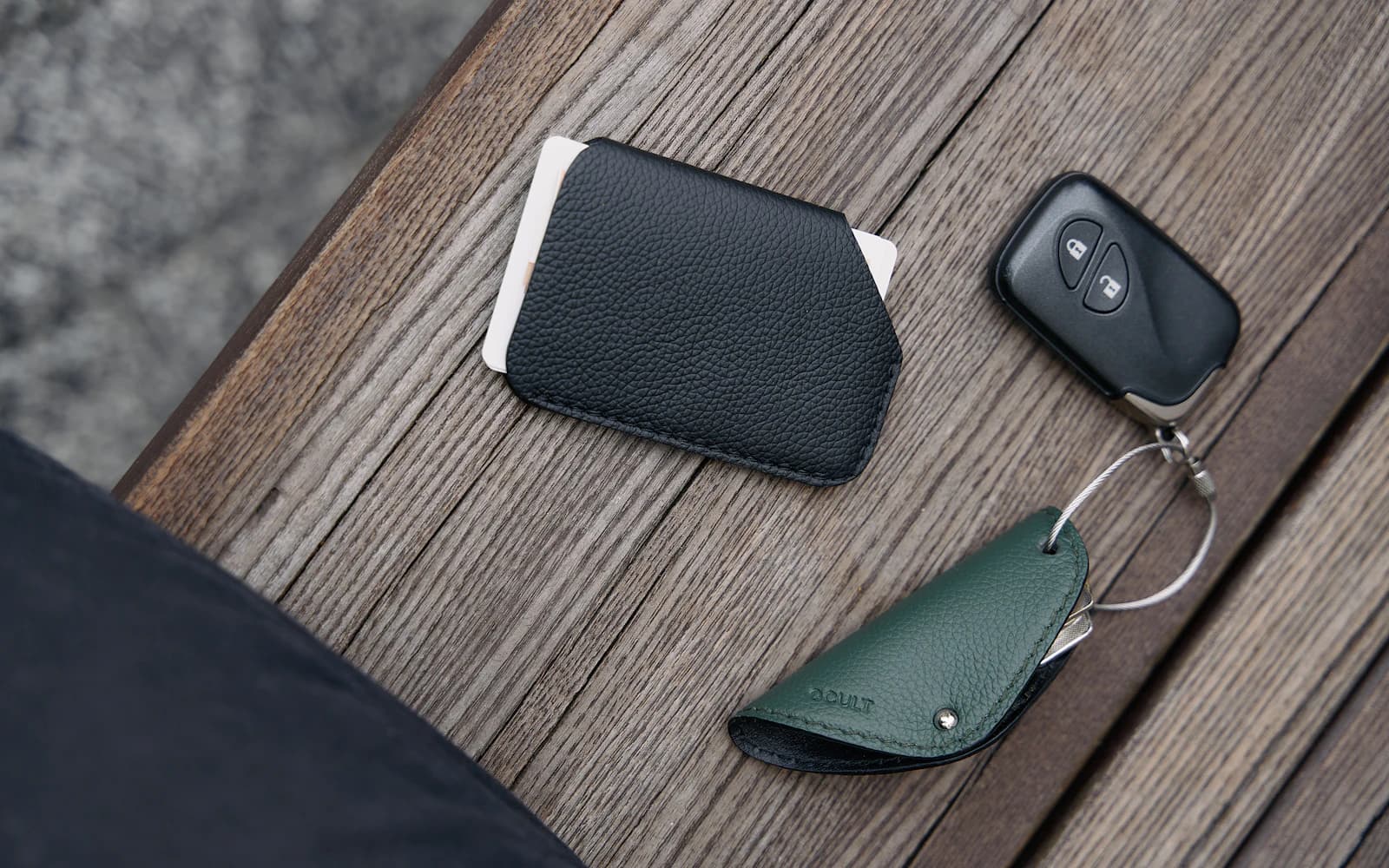 A slim wallet, payment cards, and keys arranged on a wooden table